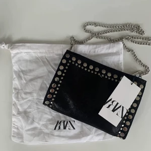 Svart zara väska - Cool zara väska med metalldetaljer. HELT slutsåld på Zaras hemsida💗 fint skick förutom att kjedjan har blivit lite bronsfärgad på vissa ställen men inget man ser. Skriv för frågor, fler bilder eller om du vill köpa!💗 Vet inte vad frakten blir än