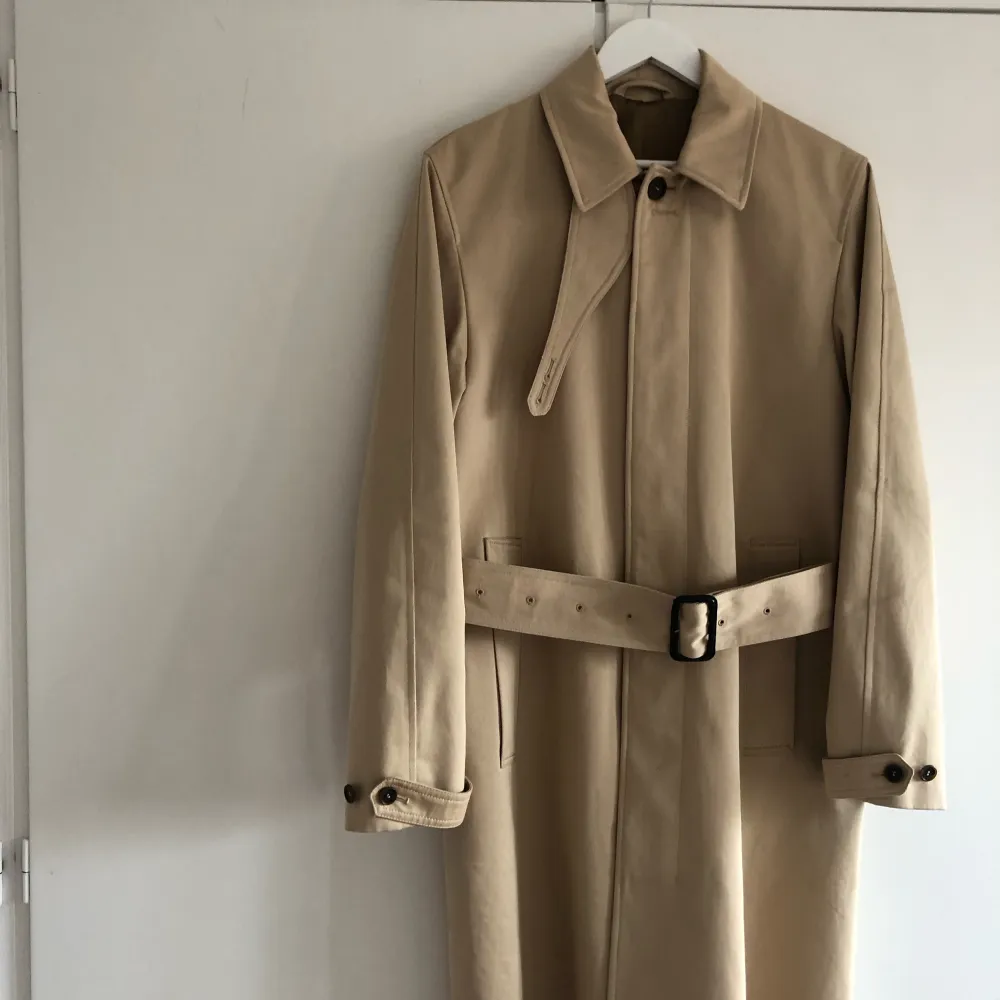 Trenchcoat i klassisk rak passform med bälte i midjan. Rocken ner till knäna om man är runt 175 cm lång. Rocken är även vattenavvisande . Jackor.