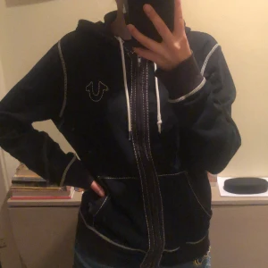 Svart True Religion Hoodie - Svart True Religion Hoodie. Använd men fortfarande i bra skick. En liten metallgrej saknas på ett av snörena. Frakt tillkommer🖤OBS! Det är spegeln som är skitig inte hoodien.