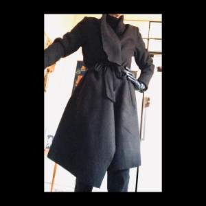 Warm black coat with huge lapels and big pockets. Wool-like material.