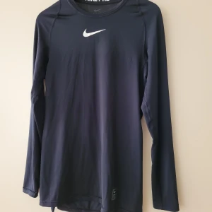 Nike Pro träningströja  - Svart Original Nike Pro Dri-fit  träningströja/undertröja i superskönt material. Använd, välvårdad. Som ny förutom en tunn reva i ryggen,  men inget som stör! Stl.M herr, slim modelll. Passar perfekt till tjej stl.M. Nypris 450:-