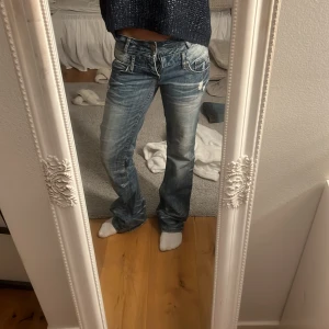 Lågmidjade blå jeans  - As balla lågmidjade jeans med slitningar.  Gylfen är sönder. 