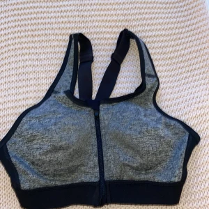Sport-bh med extra stöd - En fin sportbehå med extra stöd för brösten då det är en riktigt bh fast med ett tyg utanpå som du drar ihop med ett blixtlås. Gör så att den sitter där den ska och håller dem på plats. Storlek 70C. Köpt på stadium är från SOC. Pris kan diskuteras!