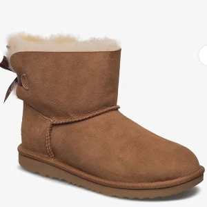 Bruna/beiga uggs med rosett - Säljer mina jättefina uggs pågrund av att de tyvärr är för små😩 Använda flertal gånger med en vattenfläck på framsidan, därav det billiga priset. Annars är de i bra skick!