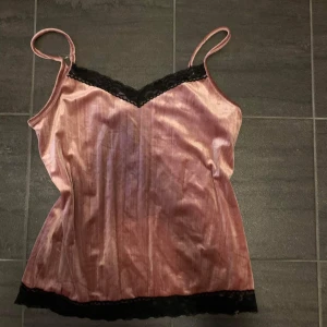 Rosa linne med spets - Linne i sammetsliknande material med svart spets. Lite trasig söm på ena axelbanden, kan skicka bild vid efterfrågan. Säljer då den blivit för stor för mig. Köparen står för frakt. 