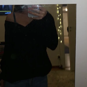 Svart stickad tröja  - En svart stickad tröja som visar axeln och har använt den Max 10gånger 