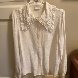Blus med volangpartier - VILA - Blus med volangkant runt kragen, ifrån VILA. I storlek Small. 