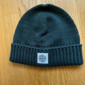 Stone Island mössa skogsgrön strl. 3 junior - En mössa från Stone Island i junior strl. 3 passar vuxna och barn sitter som S/M. Den är använd fåtal gånger i mycket bra skick. Köparen står för frakten. 