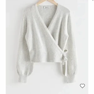 Cardigan  - Ljusgrå stickad cardigan med knytning i midjan. Använd ändas en gång, nyskick. Köpts för 490 kr.