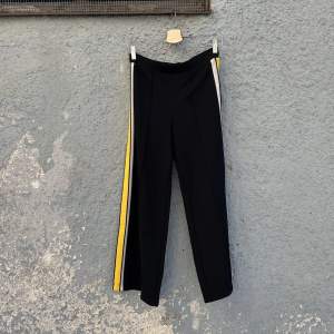Svarta byxor med gula revärer. Bekväm och stretchig trikå. 96% polyester, 4% elastan. Älskar dessa byxor men upplever attt de är för korta för mig (176cm med långa ben). Swish is queen 🌞🌻