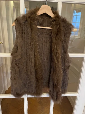Brun pälsväst (äkta) - Brun supermjuk väst i äkta päls. One size (passar storlek 34-40). Hyskknäppning och fickor. Som ny - endast använd ett fåtal gånger. 