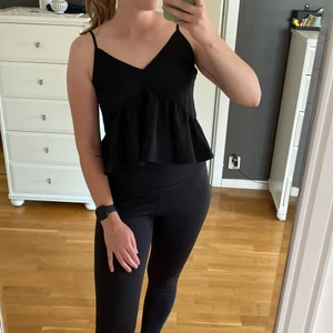 Topp från Gina Tricot  - Svart croppad topp från Gina Tricot i storlek S, passar även XS. Justerbara axelband. Volang runt om.