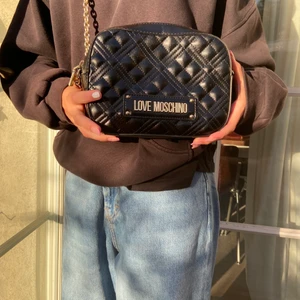 Love Moschino Axelväska - Säljer min äkta Love Moschino axelväska med guldkedja. Nästintill oanvänd, alltså superfint skick. Säljer pågrund av att den aldrig används. 500kr + frakt. Nypris ca 1400kr. Betalning sker via swish.