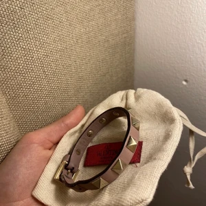 Beiget Valentino Armband - Säljer mitt fina Valentino armband! Det är ganska använt men ser väldigt fräscht och nytt ut. Denna färg passar verkligen till allt och älskar detta armband! Bud från 1000 kr! Kan tänka mig att byta mot ett mörk grönt med svarta nitar eller ett blått med svarta nitar om någon har! Kommer med dustbag. Vill bara få det sålt, så pris kan diskuteras! Köparen står för frakten.