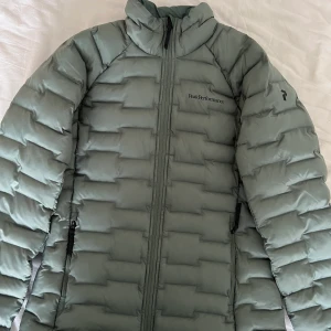 Peak Performance fodrad jacka - Grön syntetiskt fodrad jacka, toppen som mellanlager men funkar också bra att ha bara den. Använd 1 gång så den är i helt nyskick! Storlek S Dam. Nypris 2299kr.