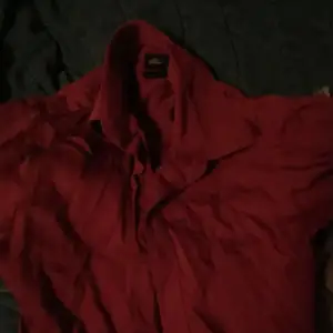 En mörk röd Skjorta som är oanvänd på ett lågnt tag men fortfarande är i god kvalité Storlek är 34/35 extra small