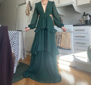 Grön långklänning med volang - Grön långklänning från Asos Design, storlek 36/S, använd två festtillfällen. Superfin skogsgrön färg med volang, dragkedja på nederdelen baktill och knappar längs ryggen upptill! Superfin till fest/bal/bröllop å liknande 🫶