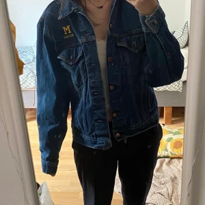 Varsity jeansjacka  - Jeansjacka med Michigan universitets tryck på. Köpt second hand men har själv knappt haft på mig den. Kan mötas i Örebro, annars står jag ej för frakt.