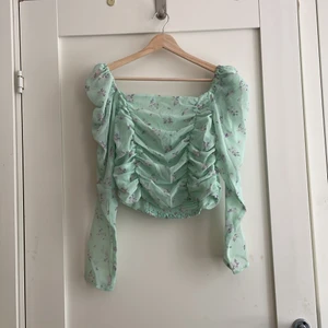 Smockad topp från H&M - En smockad, långärmad topp i mintgrönt med lila blommor på från H&M Divided 