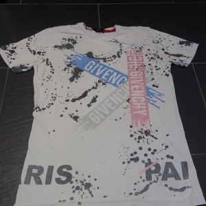Givenchy tee S - Givenchy t-shirt i röd blå och grå med paljetter. Många av paljetterna har gått bort eftersom jag har haft den ett bra tag. Det står M på tröjan men tycker den passar bättre som S.
