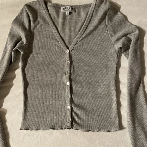 Grå topp med knappar - Grå topp med små knappar. Väldigt användbar då den passar till allt. Inga defekter. Köparen står för frakt. 