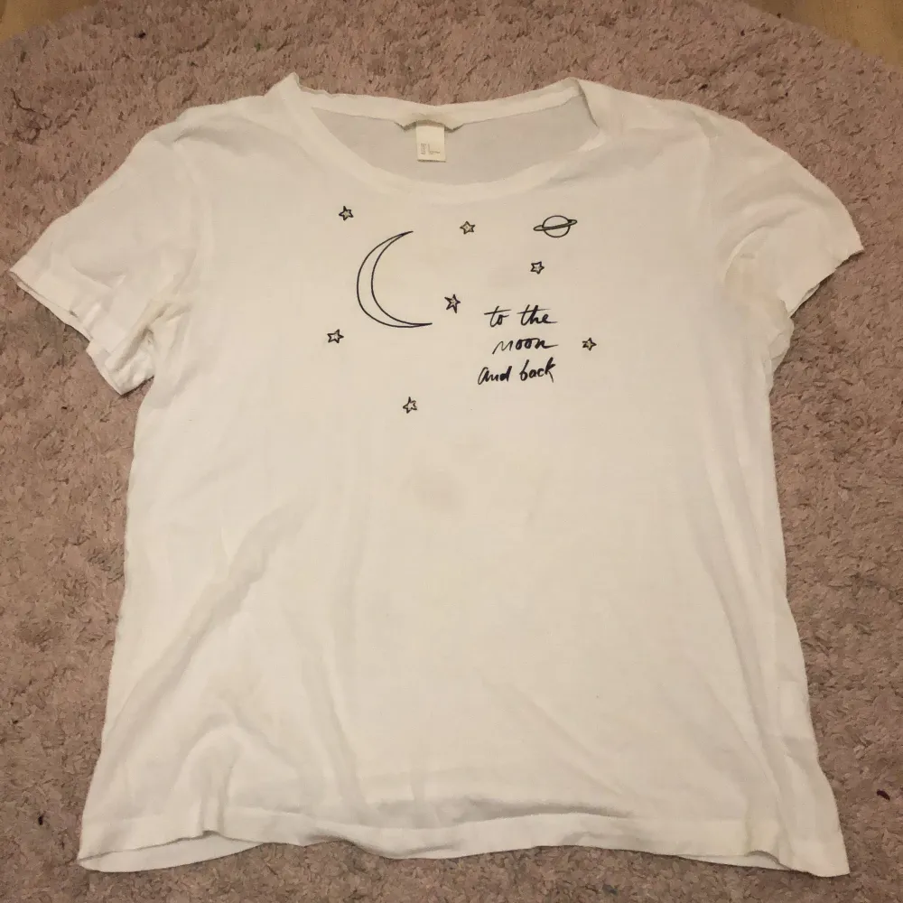En t-shirt från hm med tryck där det står ”to the moon and back” tillsammans med en måne, en planet och små stjärnor. Det finns en liten fläck på framsidan som knappt syns.. T-shirts.