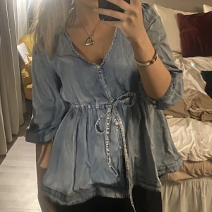 Jeans blus - Super söt o snygg jeans blus med band i midjan som framhäver ens midja såå snyggt. Även as smickrande v ringning