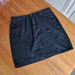 Jeanskjol Monki  - Tjusig svart jeanskjol från Monki. Pennkjolsmodell. Sparsamt använd. Gott skick.  Kort modell med hög midja.