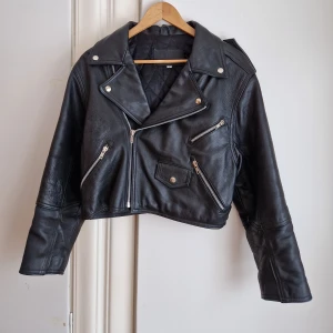Vintage skinnjacka Dam - Vintage skinnjacka i nyskick!Gissningsvis 80-/90-tal. Kvalitetsskinn (nöt) med foder i nylon. På utsidan syns det inte ens att den är använd. På insidan finns några mindre slitningar i fodret, längst ner mot midjan (bilder kan skickas) 50 cm över bröstet