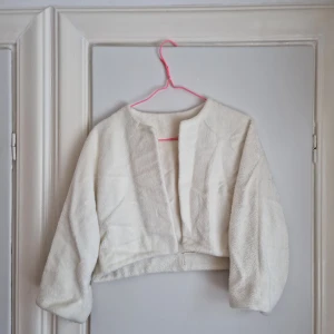 Vintage kort jacka/tröja i teddy - Vintage liten "jacka" tröja, gissningsvis 50-/60-tal. Vit korthårigt teddy-material. Trekvartsärm. Mörkt som stl 40. Passar en stol 38/40/42 eller M/L. Gott skick. Små spår av att ha varit använd och älskad. 