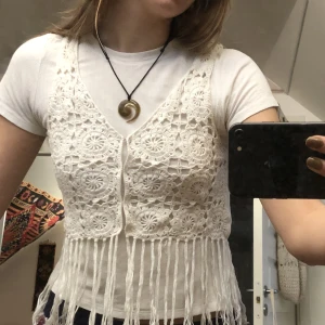 Virkad väst med fransar - Vit virkad väst med fransar köpt second hand. Inga tydliga defekter än aningen gulnad, annars i bra skick. 