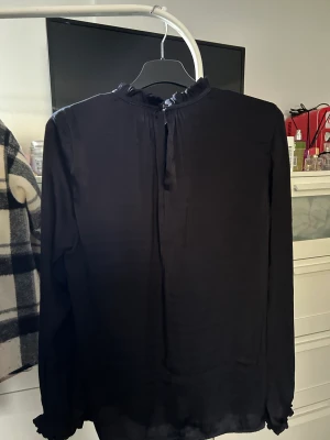 Blus - Jättefin svart blus i strl XS, har fina små volanger vid kragen och i slutet av ärmarna! 🥰säljer för 50kr +frakt 