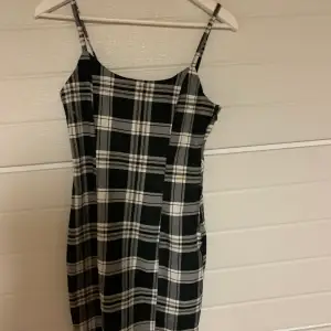 En kort rutig klänning med svart,vit och ljus brunt rutmönster 