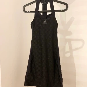 Tennisklänning/padelklänning  - Svartt sportklänning från adidas i strl XS. Mått från axel och neråt ca 80-82 cm.  Köparen betalar frakten