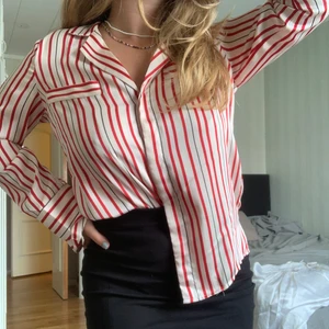 Gina Trico skjorta - Randig skjorta i silkesimmitation. Längre ärmar med slits, dold knäppning fram. OBS lite tråd i ena ärmen som ”gått upp”, se bild.