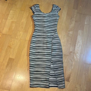 Vintage stretch klänning - Randig svart vit klänning i mjukt material. Mycket bekväm och passar till både dag och kväll. Den vita tonen är mer åt benvit än klarhet. Den har en liten slits framtill. 