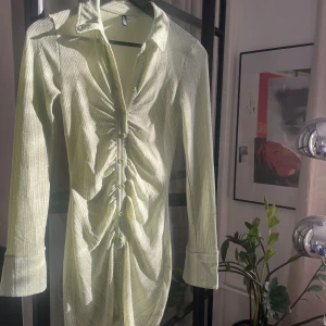 Tight klänning från H&M - Oanvänd klänning från H&M Divided. Ljust grön med silverränder.