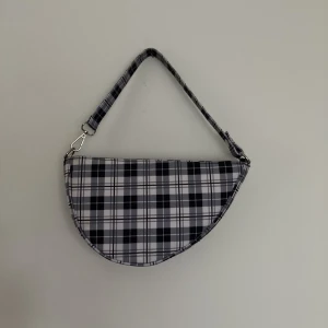 Asymmetrisk rutig handväska - Så fin asymmetrisk väska i rutigt mönster, köpt i Hong Kong. Ytan är glatt så den är lätt att hålla fräsch. 