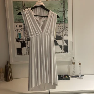 Klänning - Superfin vit klänning, som man kan knyta exakt som man vill, både runt midjan eller på olika sätt runt hals och armar! Är öppen i ryggen. Aldrig andvänd lappen finns kvar på. Funkar som både stl S och M