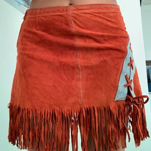 Orange läderkjol med knyte och fransar - Orange läderkjol med jeans detaljer och en snörning i stl 38, märket är flora smith och har inga skador🤍