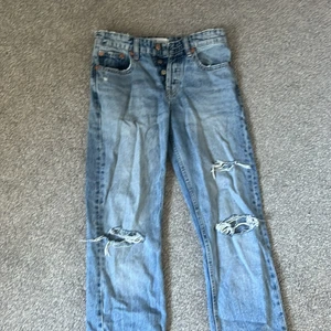 Zara jeans strl 34 - Ett par blå jeans med hål på benen, inte andvända många gånger därför i bra skick.
