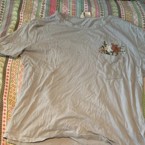 T-shitt från HM  - Blå T-shirt från HM i storlek M med fin broderiedetalj vid fickan. Köparen står för frakt.