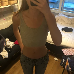 Croppat linne - Ett fint croppat linne i grå färg. Det finns ingen skada på plagget då det knappt är använt. 