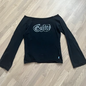 Svart off-shoulder topp utsvängda armar  - Med texten ”Guilty” superfin men använder aldrig. Texten är sprucken på flera ställen.