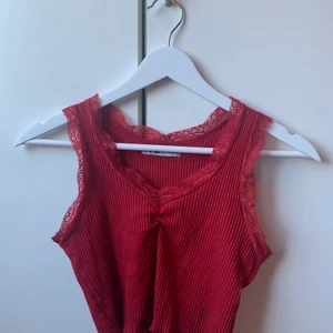 Röd topp  - rött ribbat linne med spets. jag köpte det själv på plick men det har aldrig kommit till användning. 