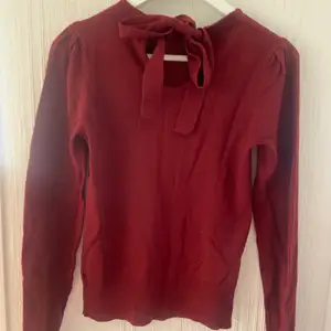Vinröd stickad tröja från HM, öppen i ryggen där man kan knyta en rosett (se första bilden). Storlek XS, kan skickas mot fraktkostnad.