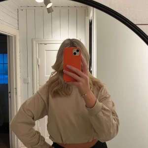 Croppad sweatshirt från Gina tricot  - Beige croppad sweatshirt från Gina tricot med dragsko nedtill 