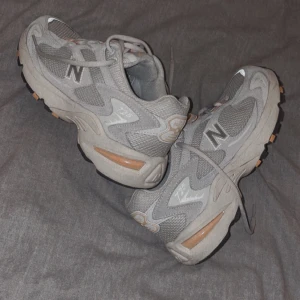 New Balance 725 (Storlek 41) - Gråa New Balance 725 skor med orangea detaljer i nyskick! Nypriset ligger på 1899kr och slutsålda överallt i den här färgen🌟
