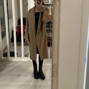 Kappa i 100% ull från H&M  - Kamelfärgad kappa från H&M trend. Använd ca 8 gånger. 100% ull. Inköpt för 1499:- för 2 år sedan. Jag är 172 lång, och kappan är till mina knän. Storlek 32, men passade mig även när jag var storlek 40-42.  