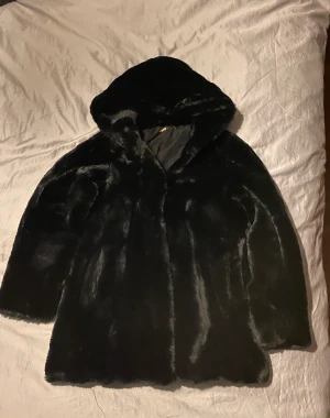 Brunsvart fuskpäls - Mjuk och härlig med huva och fickor. 